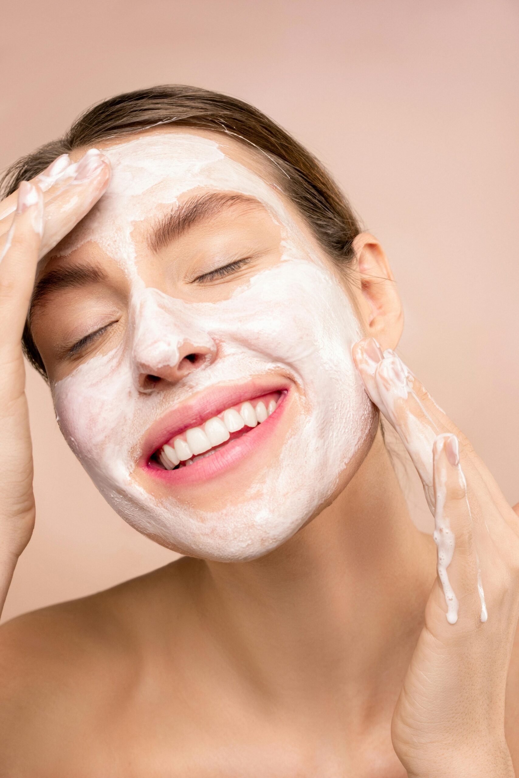 A woman enjoying a skincare routine with a facial cleanser, showcasing self-care and hygiene.